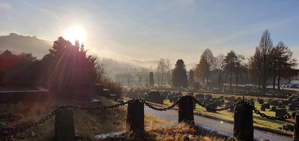 Bilde viser en kirkegård i soloppgang. Bildet er en illustrasjon for prosjektet Digital gravferdsmelding