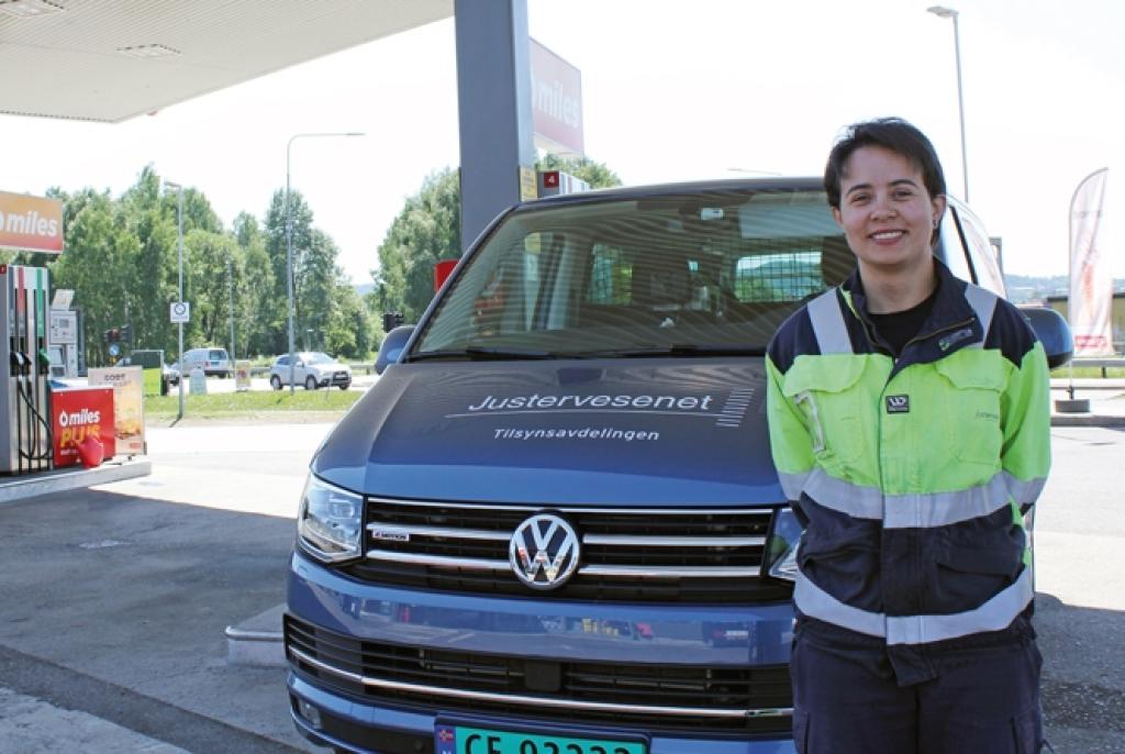 Bildet viser tilsynsingeniør Julyana Hildonen som er fagansvarlig for tilsyn med drivstoffpumper. Hun står foran en bil merket Justervesenet på en bensinsstasjon. ti